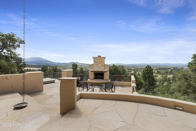 view of patio / terrace featuring a mountain view and an outdoor stone fireplace