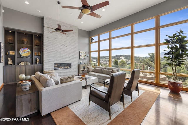 living room featuring hardwood / wood-style flooring, a stone fireplace, a mountain view, and a high ceiling