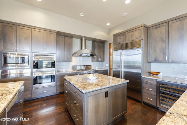 kitchen with built in appliances, tasteful backsplash, light stone countertops, dark hardwood / wood-style flooring, and wall chimney exhaust hood