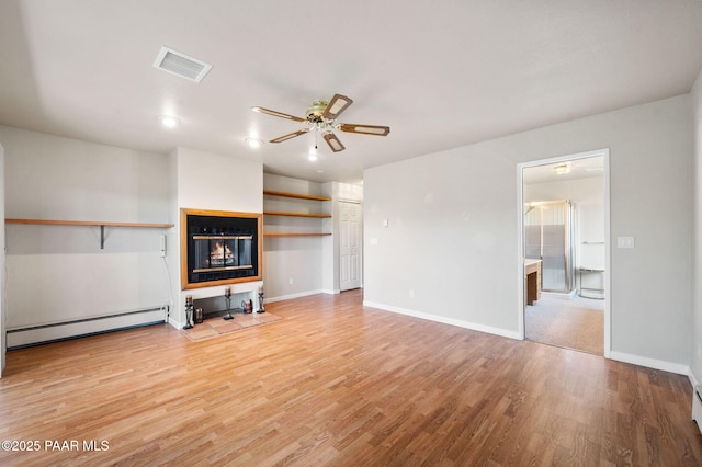 unfurnished living room featuring visible vents, a glass covered fireplace, light wood-style floors, a baseboard heating unit, and a ceiling fan