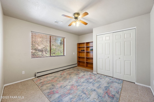 unfurnished bedroom featuring visible vents, a closet, baseboards, baseboard heating, and carpet flooring