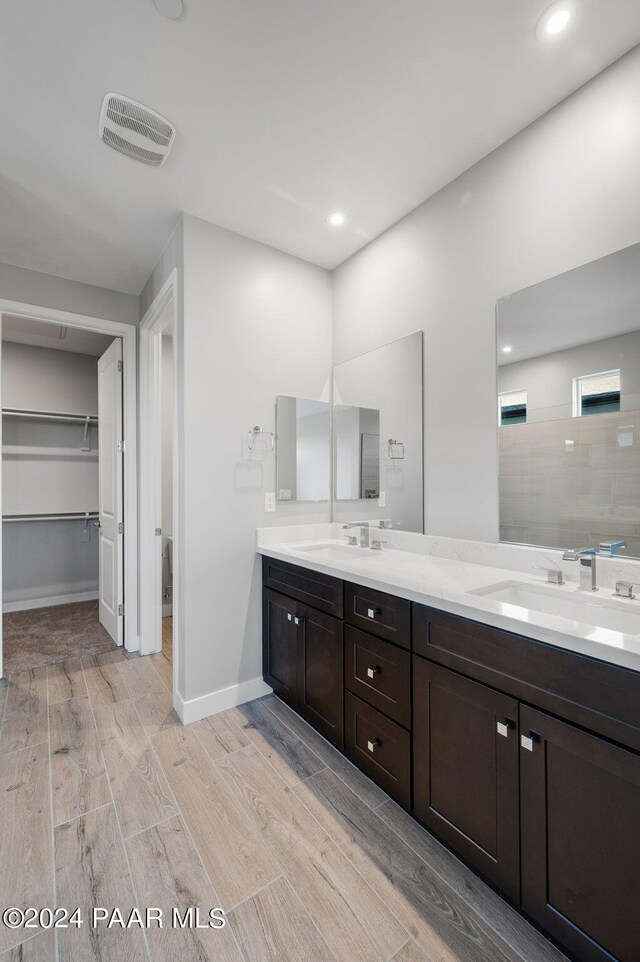 bathroom featuring hardwood / wood-style floors, vanity, and tiled shower