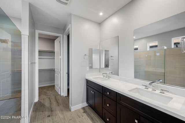 bathroom with a tile shower, vanity, and wood-type flooring