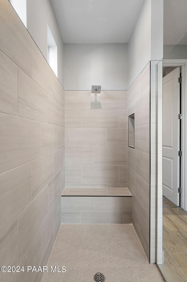 bathroom with a tile shower and tile walls