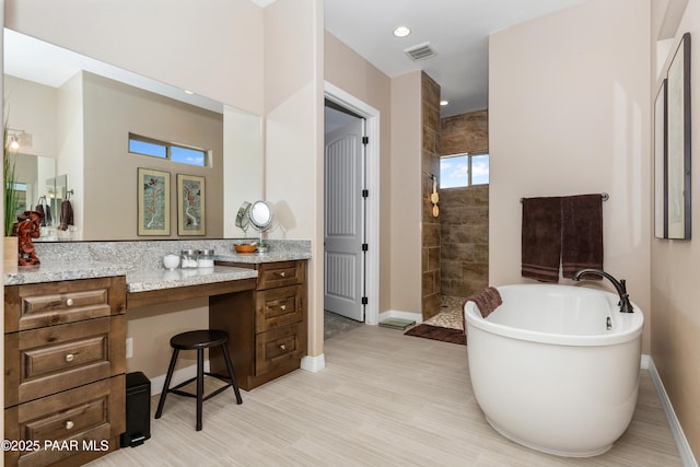 bathroom with visible vents, a freestanding bath, vanity, a walk in shower, and baseboards