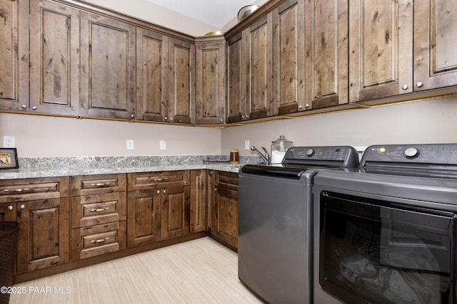 washroom featuring cabinet space, a sink, and washer and clothes dryer