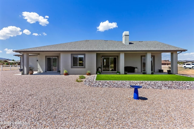 back of property with a yard, fence, stucco siding, and roof with shingles