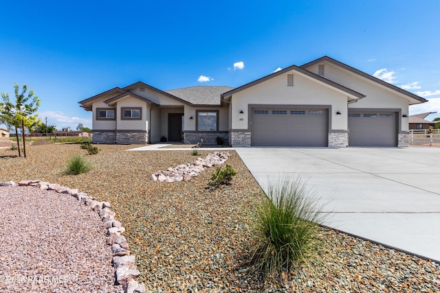 view of front facade featuring concrete driveway, stone siding, an attached garage, fence, and stucco siding