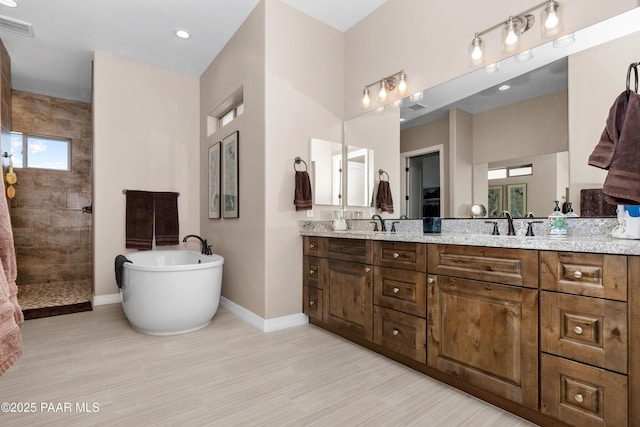 full bath with a walk in shower, visible vents, baseboards, a soaking tub, and double vanity