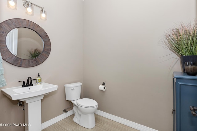 bathroom with baseboards, a sink, and toilet