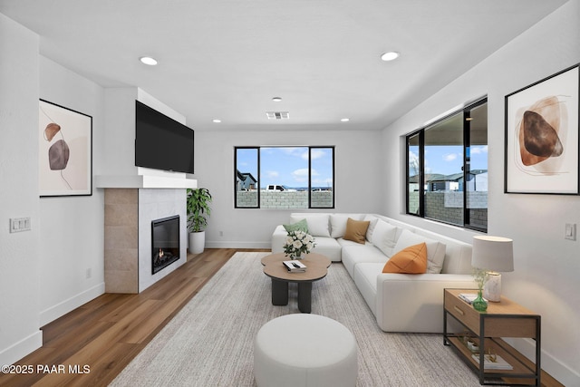 living room featuring a tile fireplace and hardwood / wood-style flooring