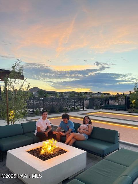 patio terrace at dusk with an outdoor living space with a fire pit