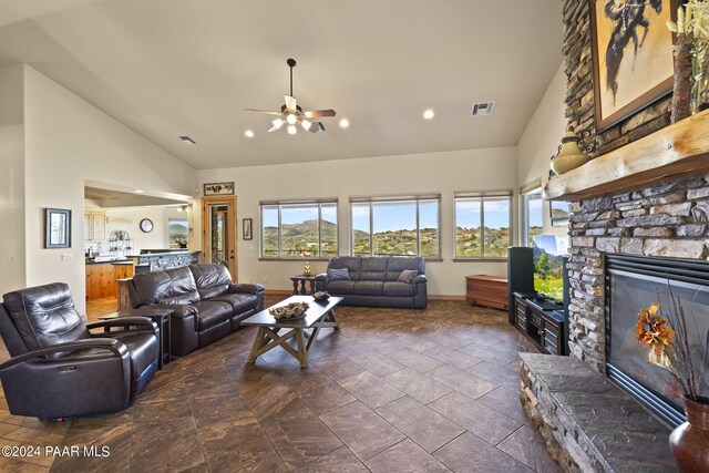 living room featuring a stone fireplace, high vaulted ceiling, and ceiling fan