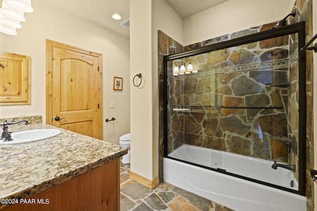 full bathroom featuring vanity, bath / shower combo with glass door, and toilet