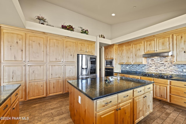 kitchen featuring black appliances, a center island with sink, dark hardwood / wood-style floors, dark stone counters, and backsplash