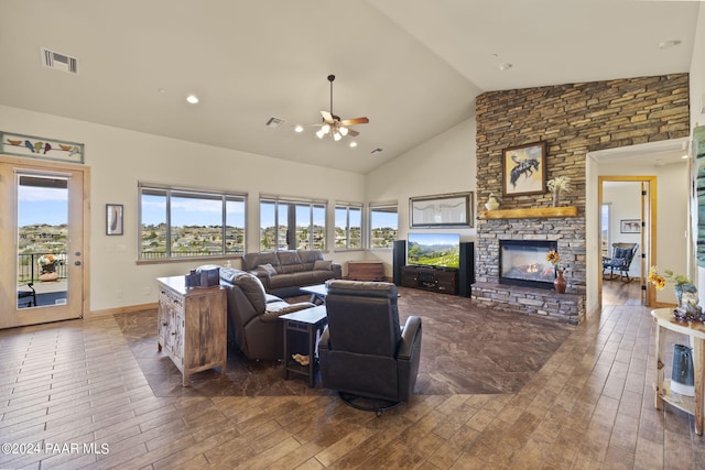 living room with ceiling fan, a stone fireplace, dark wood-type flooring, and high vaulted ceiling