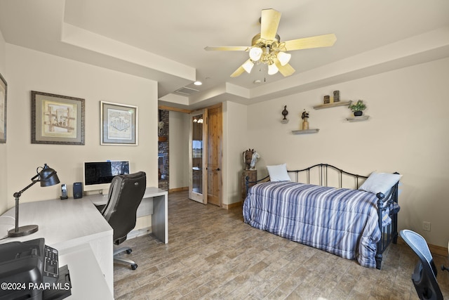 bedroom with a raised ceiling, hardwood / wood-style floors, and ceiling fan