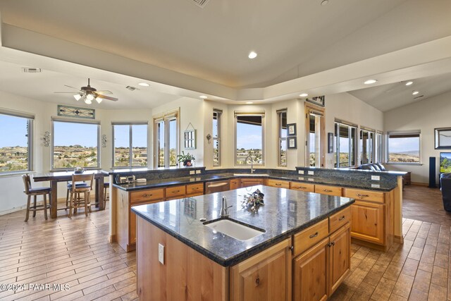 kitchen featuring lofted ceiling, sink, kitchen peninsula, and a kitchen island with sink