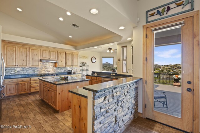 kitchen with a kitchen island, dark hardwood / wood-style floors, lofted ceiling, backsplash, and kitchen peninsula