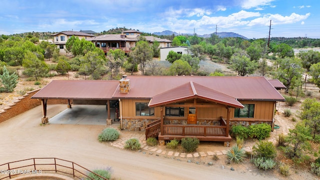 13225 N Bull Run Rd, Prescott, AZ 86305 - view of front of house with stone siding, an attached carport, driveway, a mountain view, and a metal roof