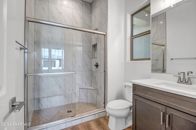 bathroom with wood-type flooring, vanity, toilet, and a shower with door