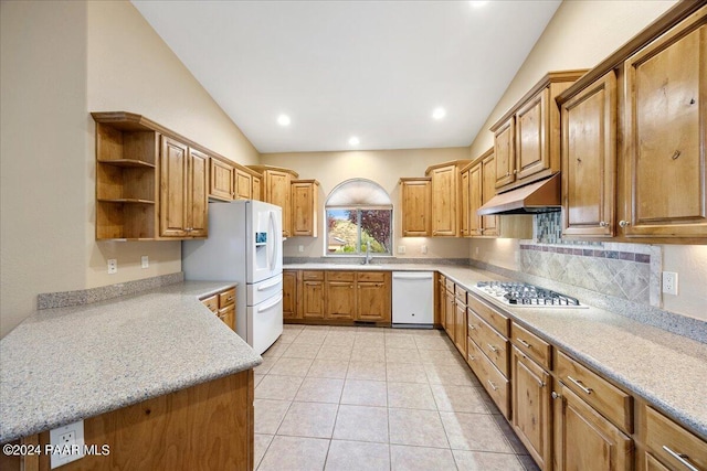 kitchen with sink, white appliances, light tile patterned floors, light stone countertops, and vaulted ceiling