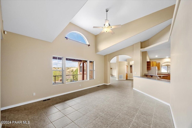 empty room with a high ceiling, tile patterned floors, and ceiling fan