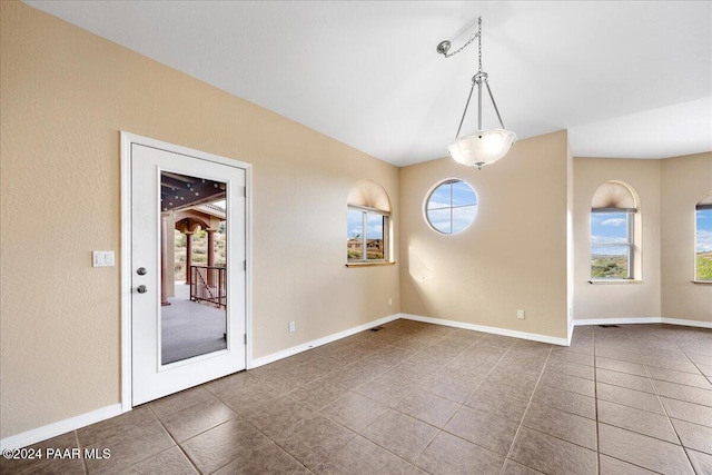 spare room with vaulted ceiling and dark tile patterned flooring