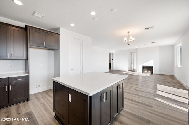 kitchen featuring a center island, hanging light fixtures, light hardwood / wood-style flooring, a notable chandelier, and dark brown cabinets