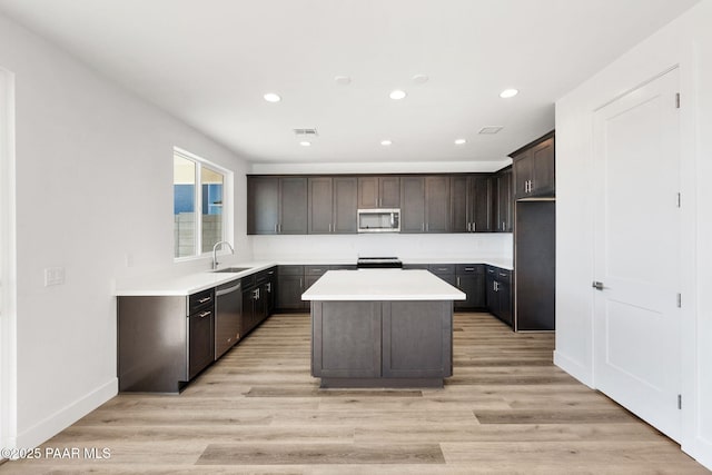 kitchen with dark brown cabinets, stainless steel appliances, sink, light hardwood / wood-style floors, and a kitchen island