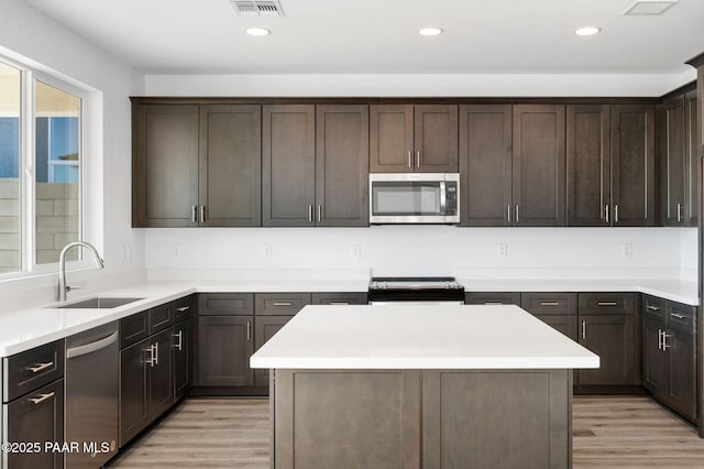 kitchen featuring dark brown cabinets, sink, stainless steel appliances, and light hardwood / wood-style flooring