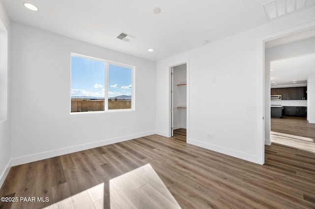 unfurnished bedroom with a walk in closet, a closet, and hardwood / wood-style floors