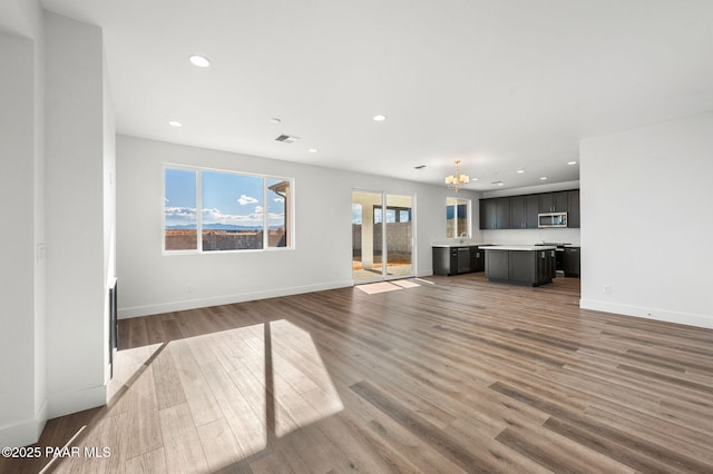 unfurnished living room featuring wood-type flooring and an inviting chandelier