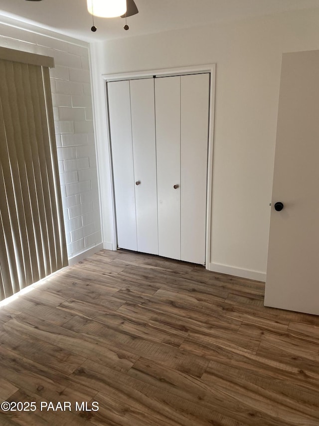 unfurnished bedroom with a closet and dark wood-style flooring