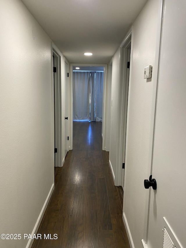 corridor with baseboards, dark wood-style flooring, and visible vents