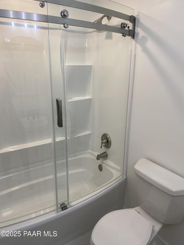 bathroom featuring toilet and bath / shower combo with glass door