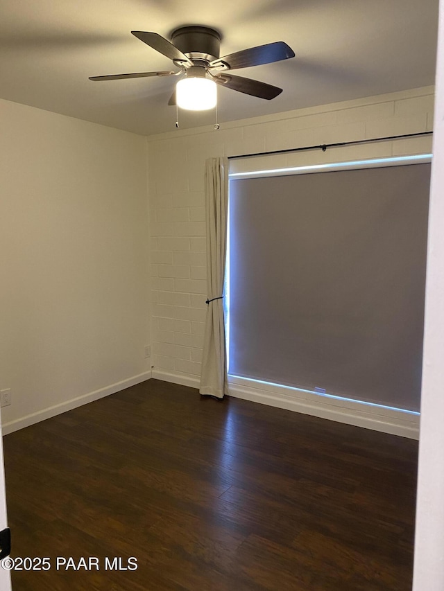 unfurnished room with a ceiling fan, baseboards, and dark wood finished floors
