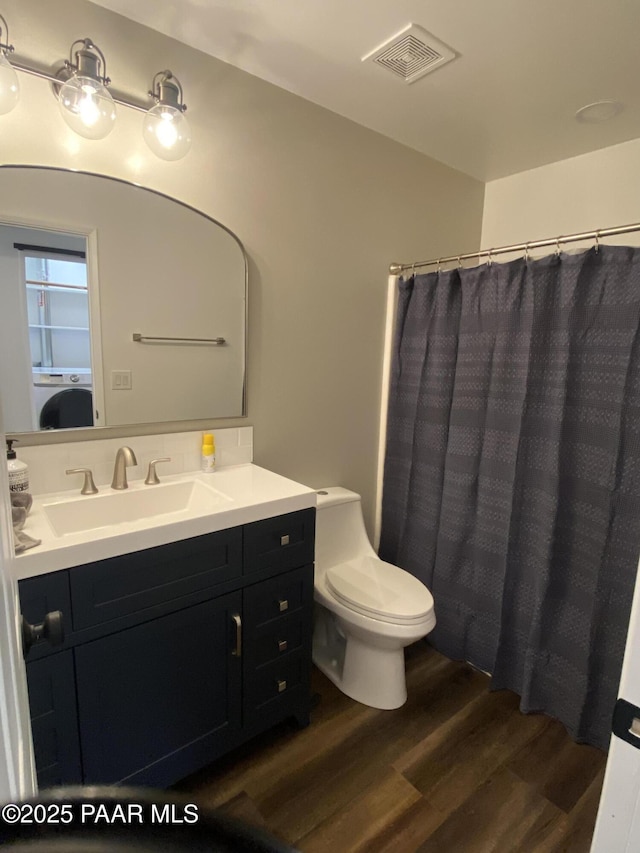 bathroom with visible vents, vanity, wood finished floors, toilet, and a shower with shower curtain