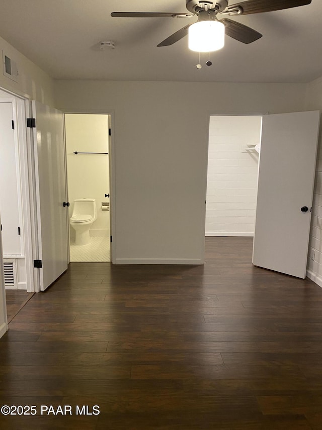 unfurnished room featuring dark wood-style flooring, a ceiling fan, visible vents, and baseboards