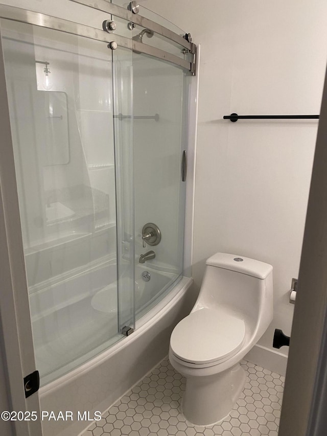 bathroom with tile patterned flooring, toilet, and shower / bath combination with glass door