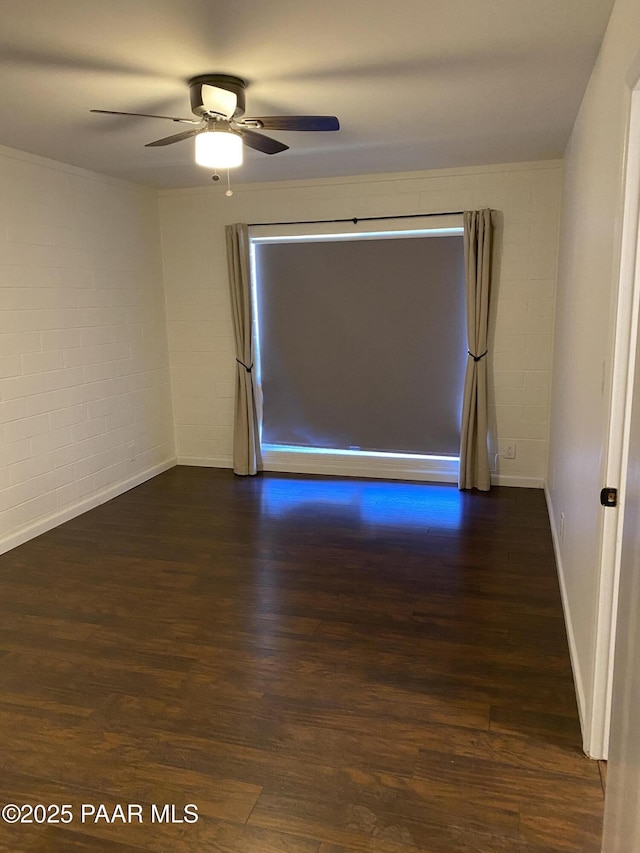 empty room featuring baseboards, ceiling fan, and dark wood finished floors
