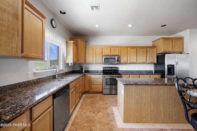 kitchen featuring dark stone countertops, sink, light tile patterned flooring, and appliances with stainless steel finishes