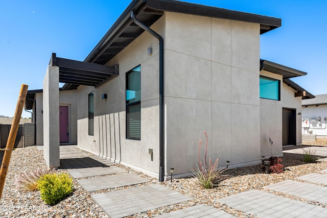view of property exterior with stucco siding and fence
