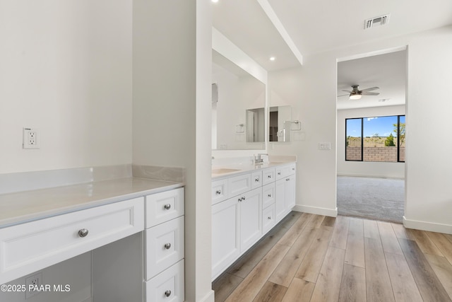 full bath with visible vents, double vanity, wood finished floors, baseboards, and a ceiling fan