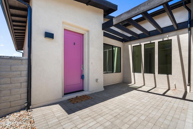 entrance to property featuring a patio and stucco siding