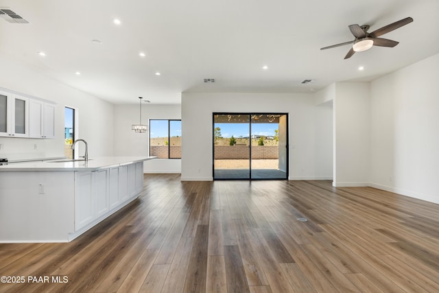 unfurnished living room with visible vents, recessed lighting, a sink, and wood finished floors