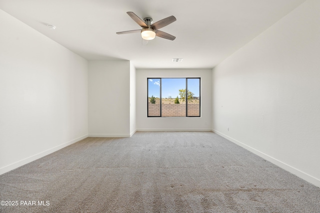 spare room with carpet floors, baseboards, a ceiling fan, and visible vents