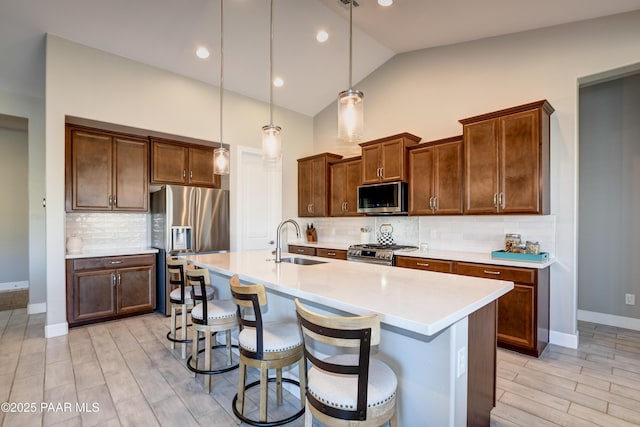 7028 Corral Ct, Prescott, AZ 86305 - kitchen featuring appliances with stainless steel finishes, lofted ceiling, light countertops, light wood-type flooring, and an island with sink