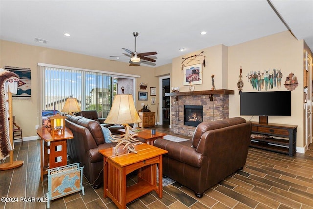 living room featuring a stone fireplace, ceiling fan, and dark wood-type flooring