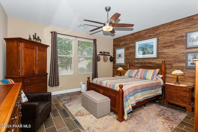 bedroom featuring ceiling fan and wooden walls